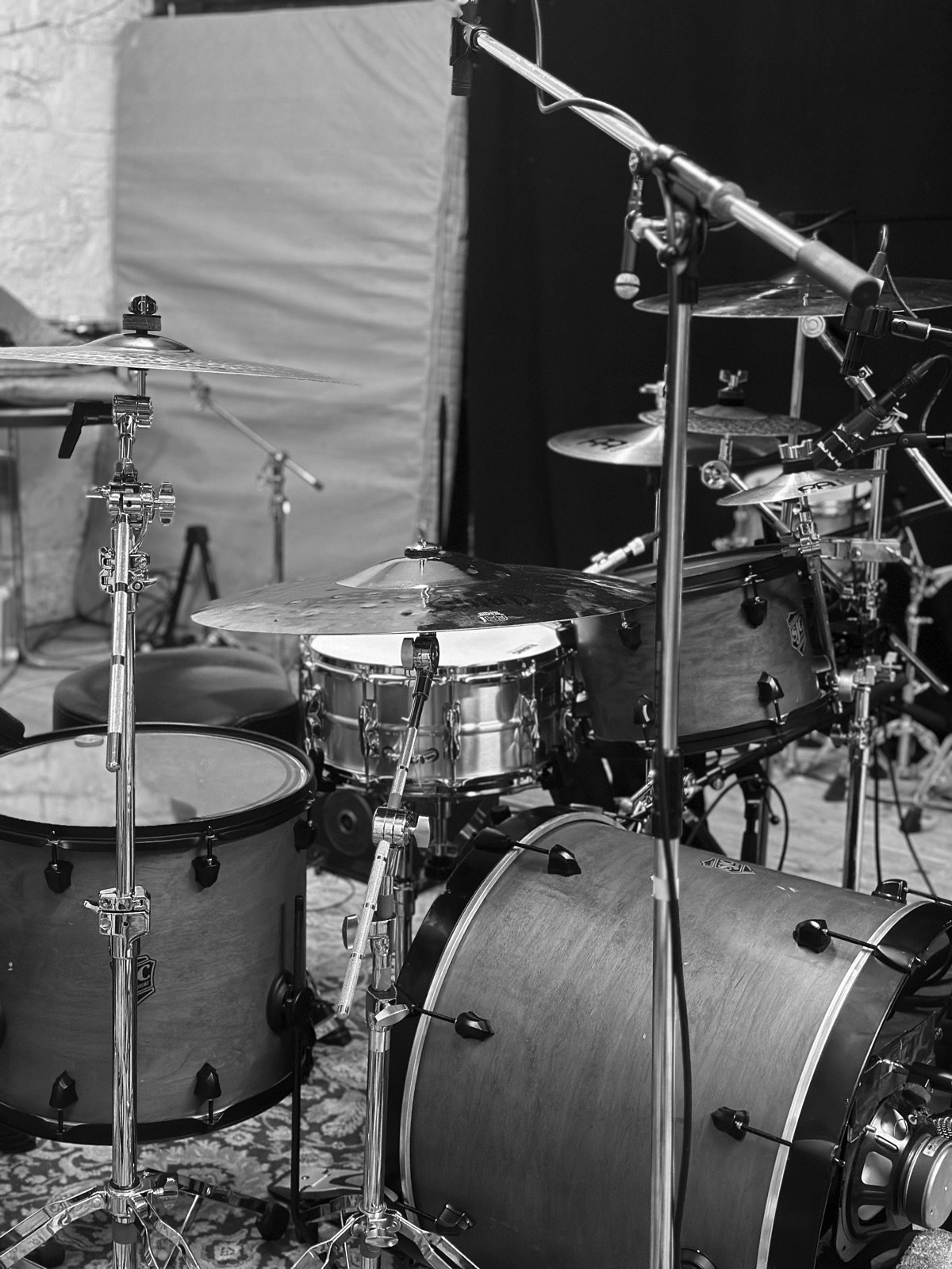 Drum kit framed vertically in the live room, black and white